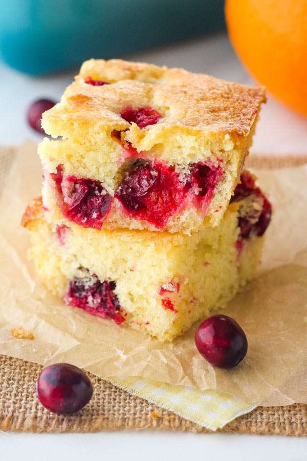 Squares of tender cake on parchment squares with whole cranberries.