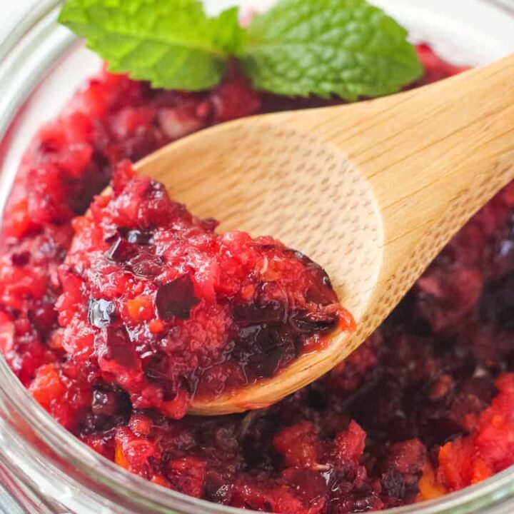 Closeup of spoon scooping a chunky cranberry relish from a mason jar.