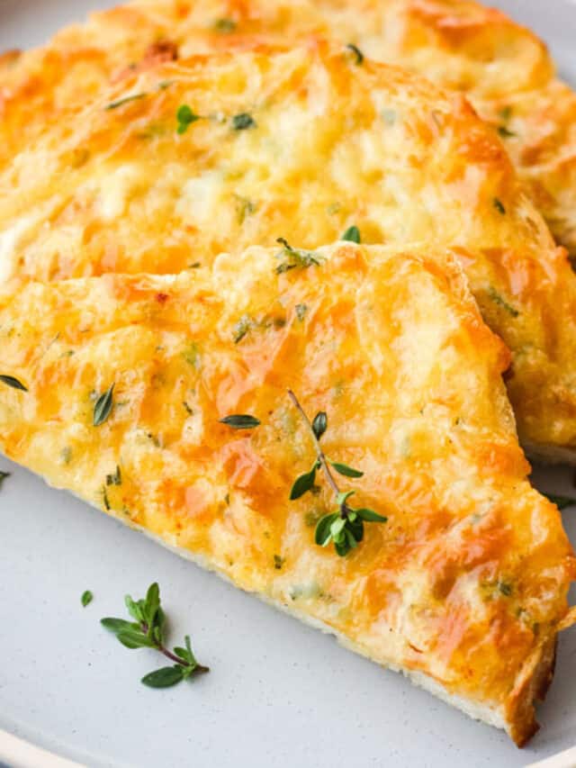 Triangles of cheesy toast on a blue plate with fresh thyme leaves sprinkled on top.