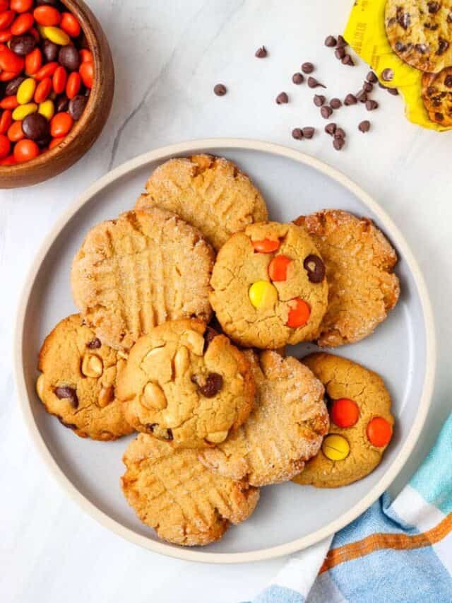 Plate of cookies with an open bag of chocolate chips and a bowl of Reese's Pieces.