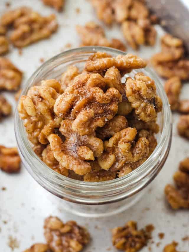 Overhead view of sparkly cinnamon walnuts in a glass mason jar.