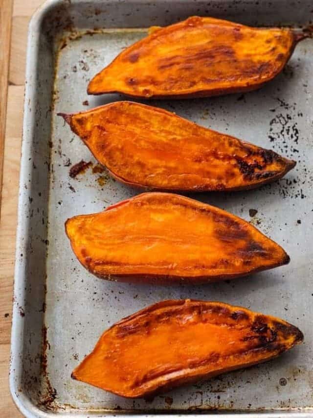 Cooked sweet potato halves on a quarter sheet pan.