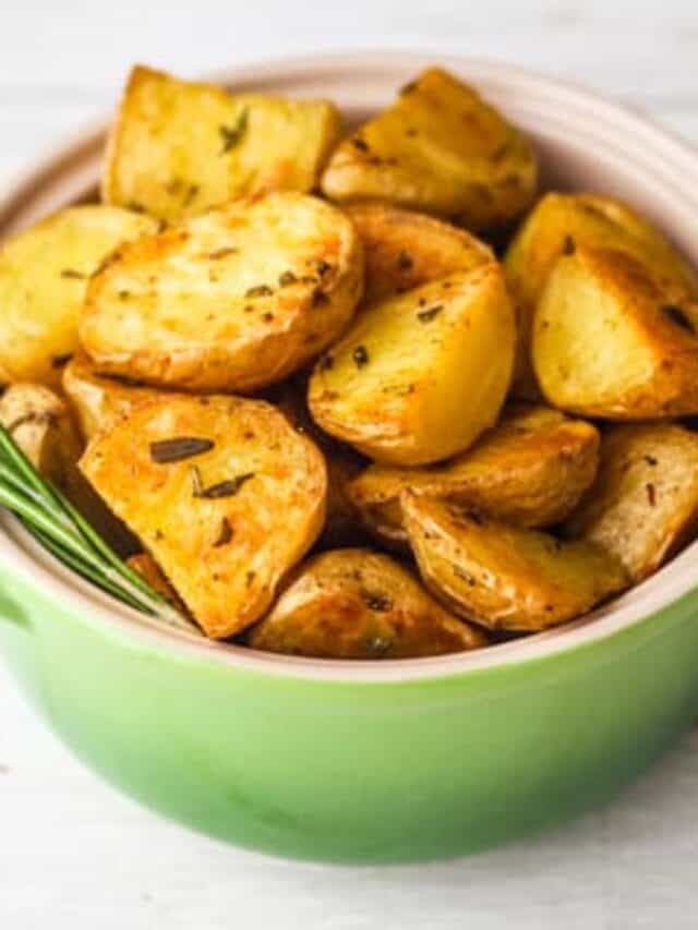 Roasted rosemary potatoes in a small green oval baking dish.