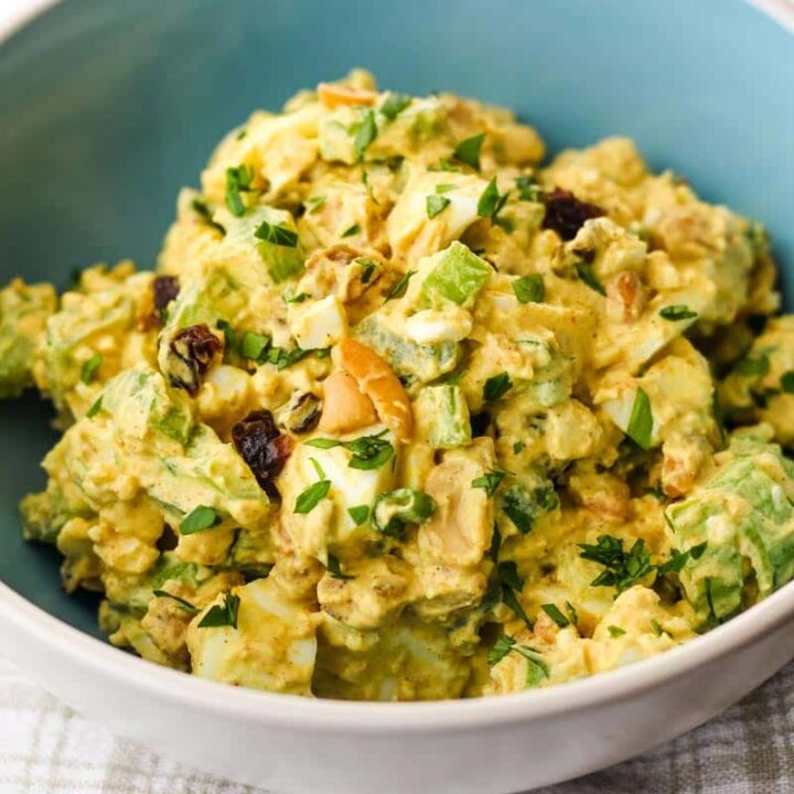 Closeup of bowl of egg salad with chopped celery, raisins, and cashews.