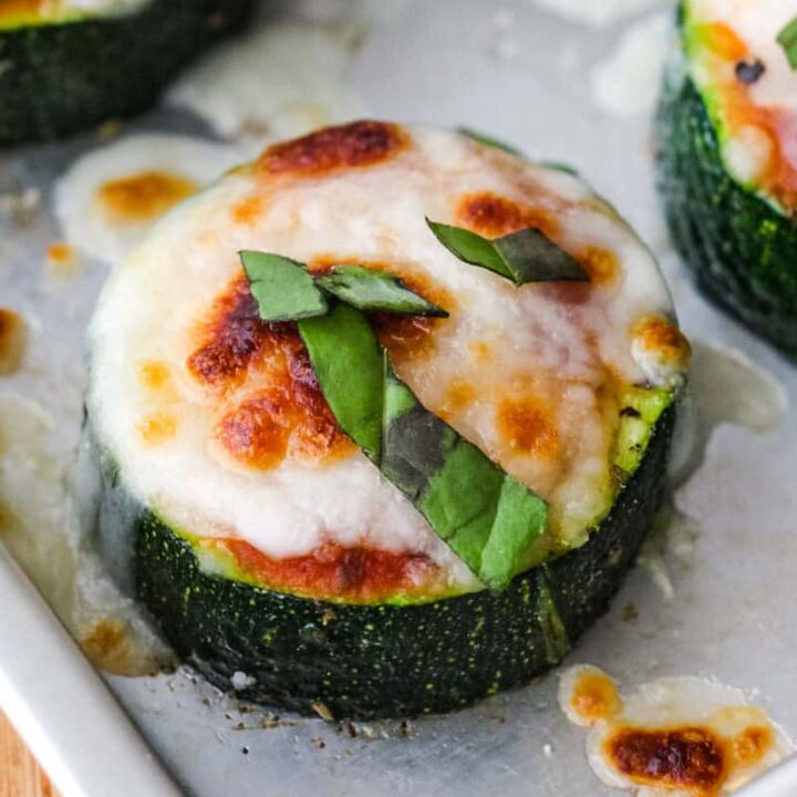 Closeup of a mini zucchini pizza with melted cheese and fresh basil.