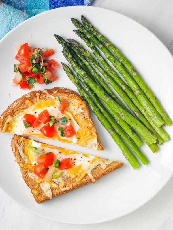 Plate of cheesy egg toast, asparagus, and pico de gallo.