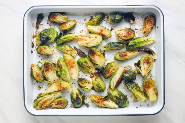 Roasted Brussels sprouts in a white rimmed pan.