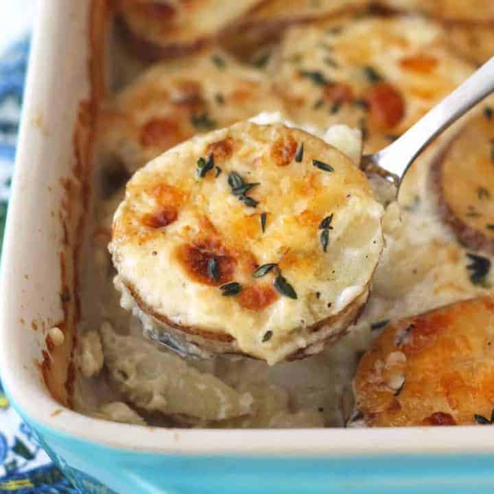 Serving spoon filled with cheesy potatoes au gratin.