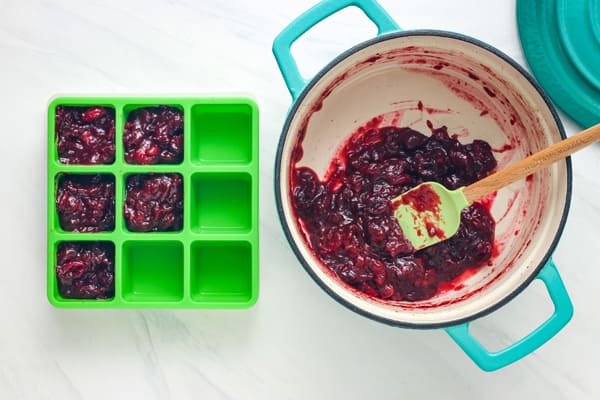 Overhead view of a small dutch oven and cube tray filled with cooked cranberries.