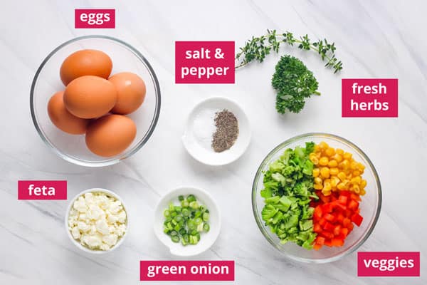 Overhead view of eggs, herbs, and other ingredients in bowls.