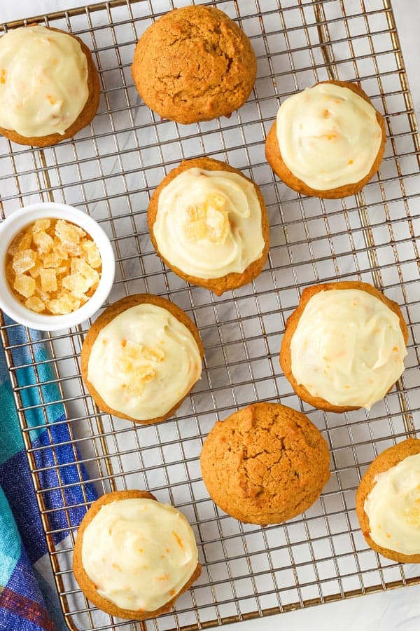 Frosted cookies on a cooking rack with a bowl of diced candied ginger.