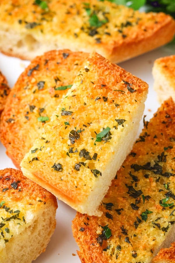 Closeup of a buttery slice of baked garlic bread.