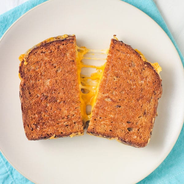 Grilled cheese on a plate, split with cheese melting from the center.