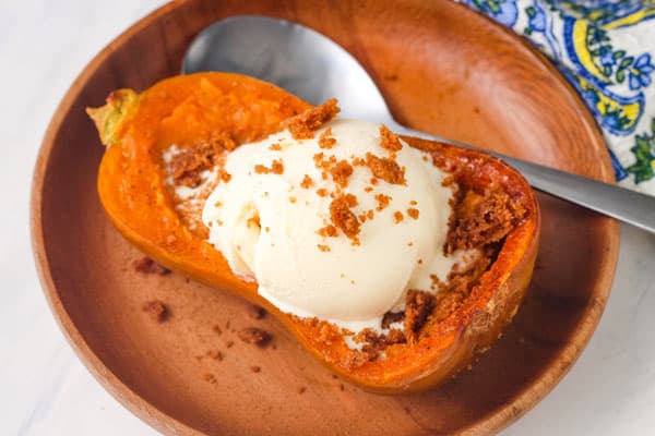 Cooked honeynut squash topped with a scoop of vanilla ice cream.