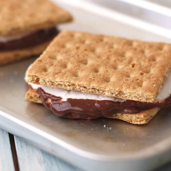 Closeup of smores with gooey marshmallows and melted chocolate on a small sheet pan.