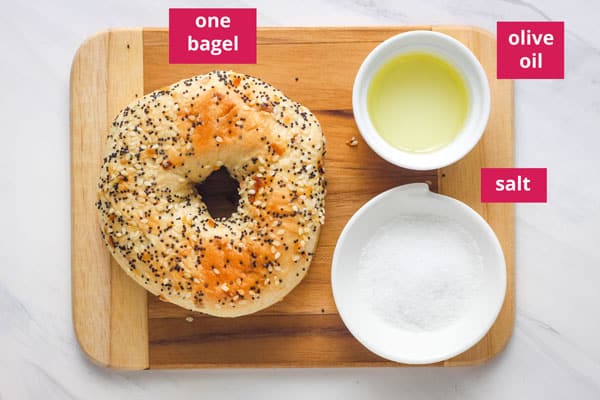 Everything bagel and ramekins with oil and salt on a cutting board.