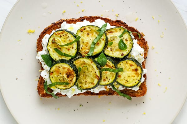 Cooked zucchini round on cottage cheese toast.