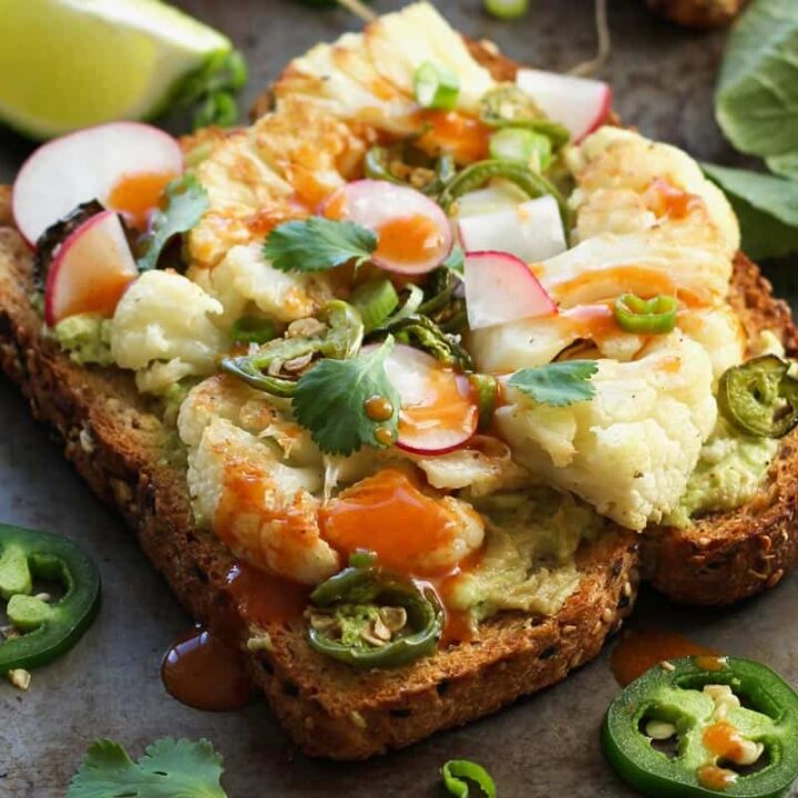 Closeup of cauliflower toast topped with hot sauce and jalapeno slices.