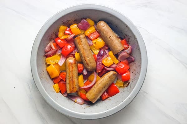 Cooked veggie sausage and peppers in a metal pie pan.