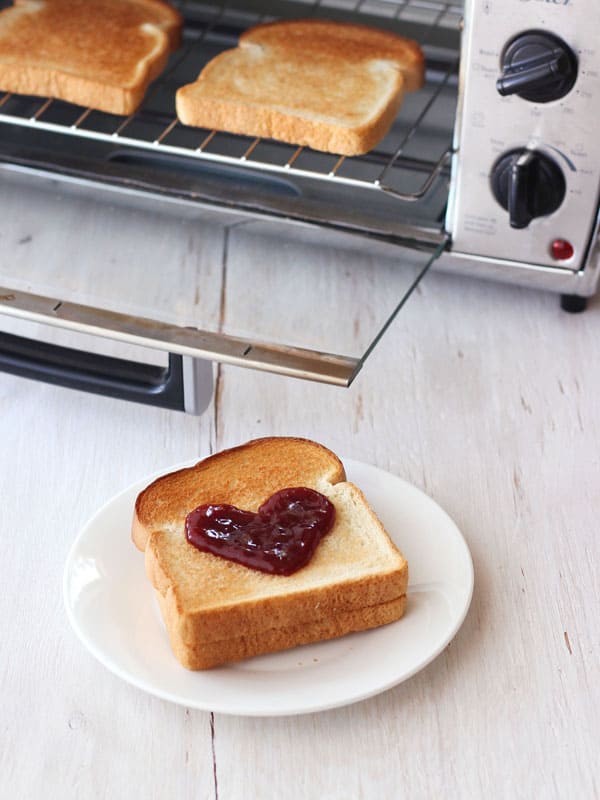 Toast with a jelly heart on a white plate.