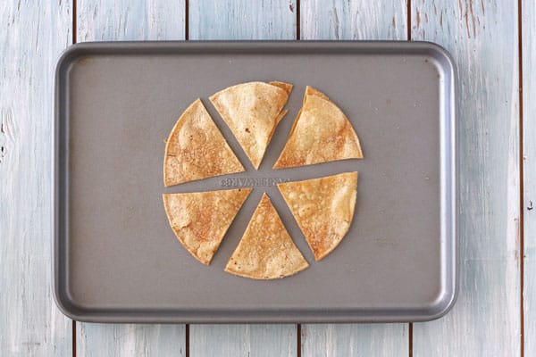 Crispy baked tortilla chips cooling on a baking sheet.