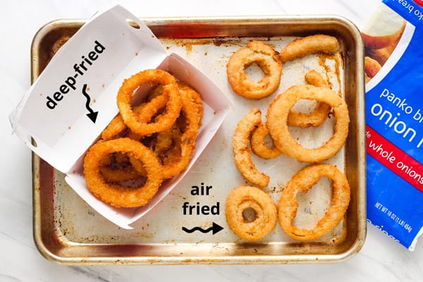 Overhead view of air fryer cooked and fast food onion rings.