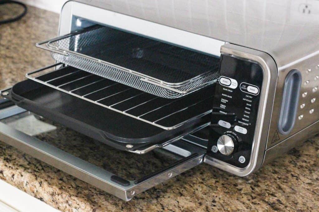 Air fry basket, cooking rack, and grill pan inside a toaster oven.