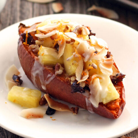 Baked sweet potato on a white plate on a wooden table.