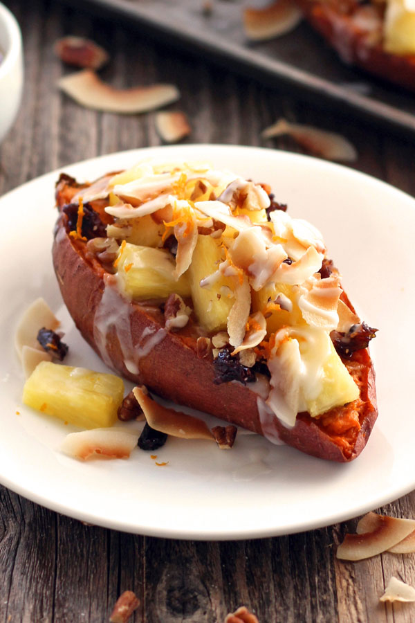 Baked sweet potato on a white plate on a wooden table.