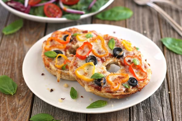 Two baked pizza bagels on a plate.