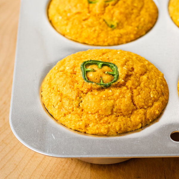 Cornbread muffins in a muffin pan on a cutting board.