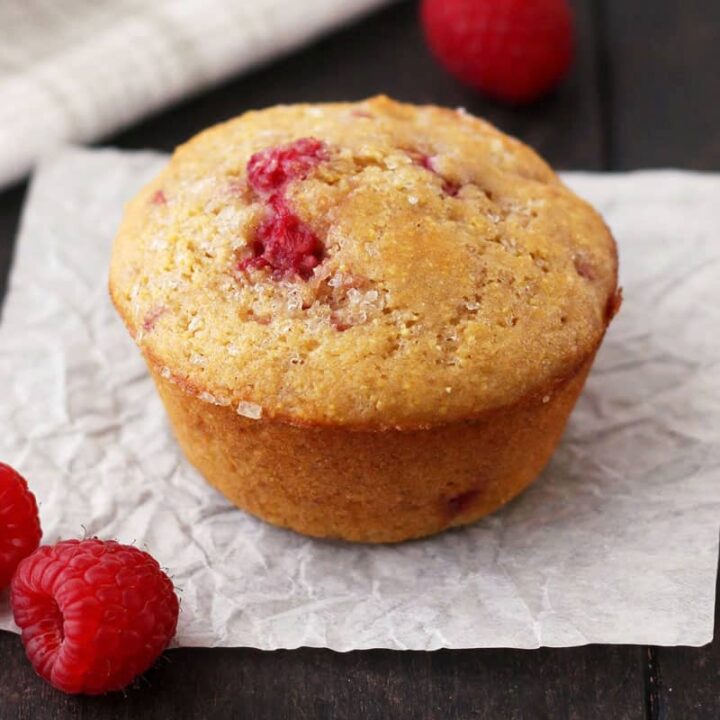 Baked muffin next to fresh raspberries on a table.