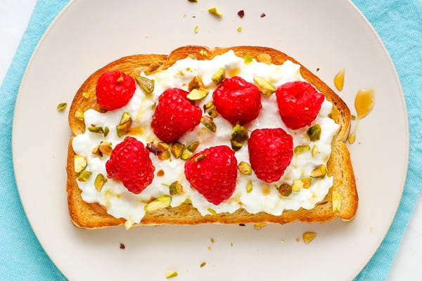 Fresh red raspberries and pistachios on sourdough toast.