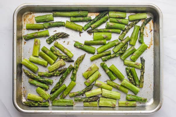 Roasted chopped asparagus on a sheet pan.