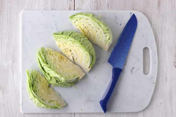 Half a head of cabbage chopped into wedges on a cutting board.