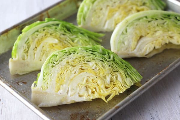 Oiled and seasoned cabbage wedges on a quarter sheet pan.