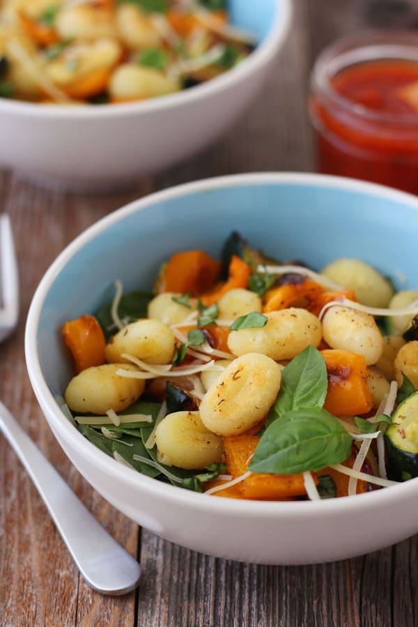 A blue bowl with gnocchi and spinach 