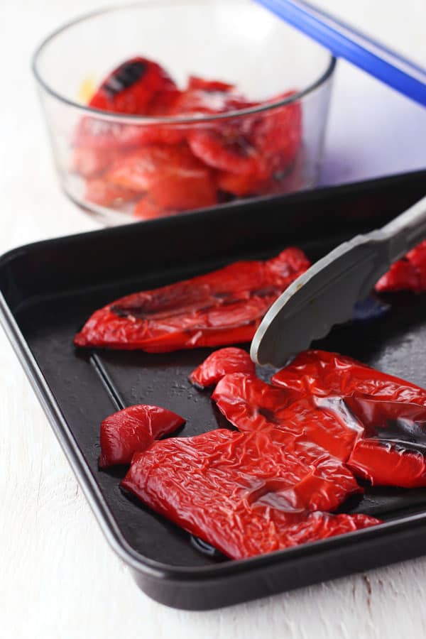 Roasted red peppers with blackened spots on a roasting pan.