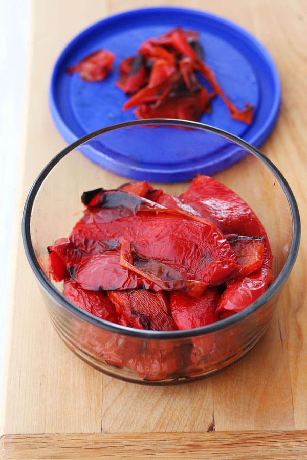 Red peppers in a bowl with their skin peeled back.