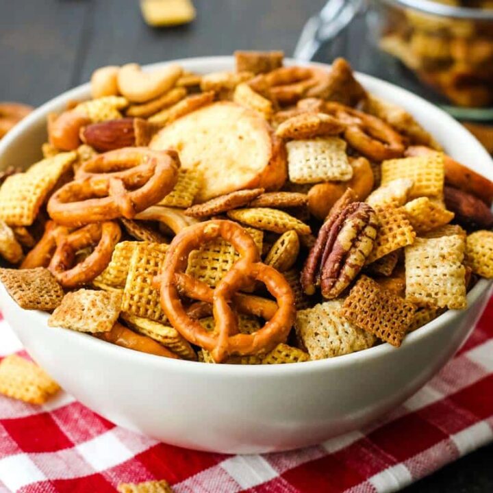 Bowl of snack mix on red checkered napkin.