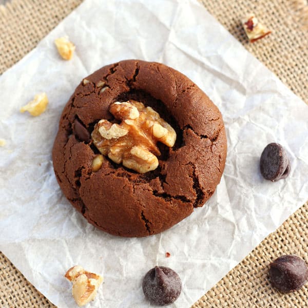 Chocolate cookie surrounded by chocolate chips and chopped walnuts.