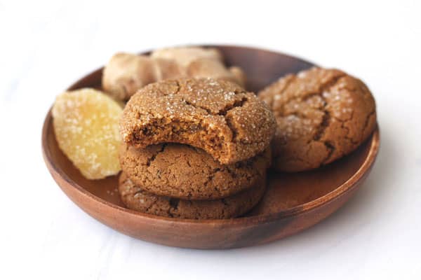 Cookies stacked in a wooden bowl with a bite taken out of one.