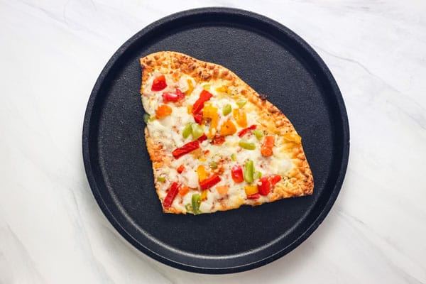 Large slice of pizza on a round cast iron griddle.