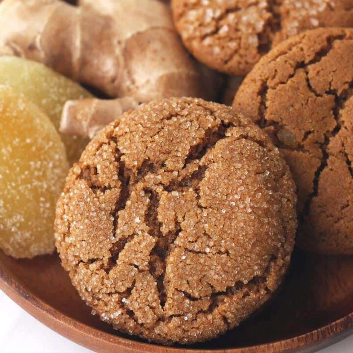 Closeup of baked ginger cookies in a bowl with fresh and candied ginger.