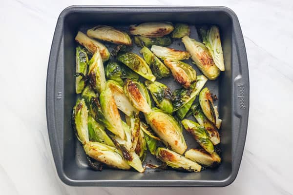 Golden roasted Brussels sprouts in a square metal pan.