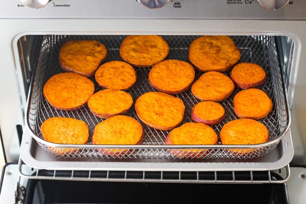 Sweet potato slices in a toaster oven air fryer basket.