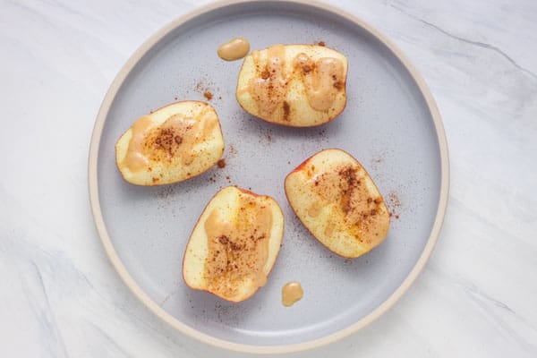 A plate of apple quarters topped with tahini and cinnamon.