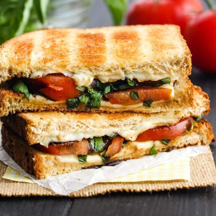 Stacked slices of tomato and cheese sandwich on a table.