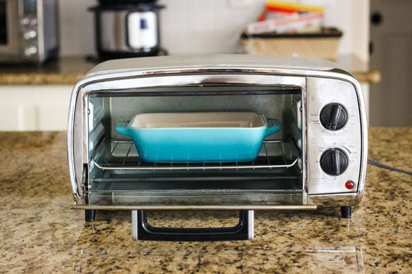 Blue 7x5 baking dish inside a small toaster oven.