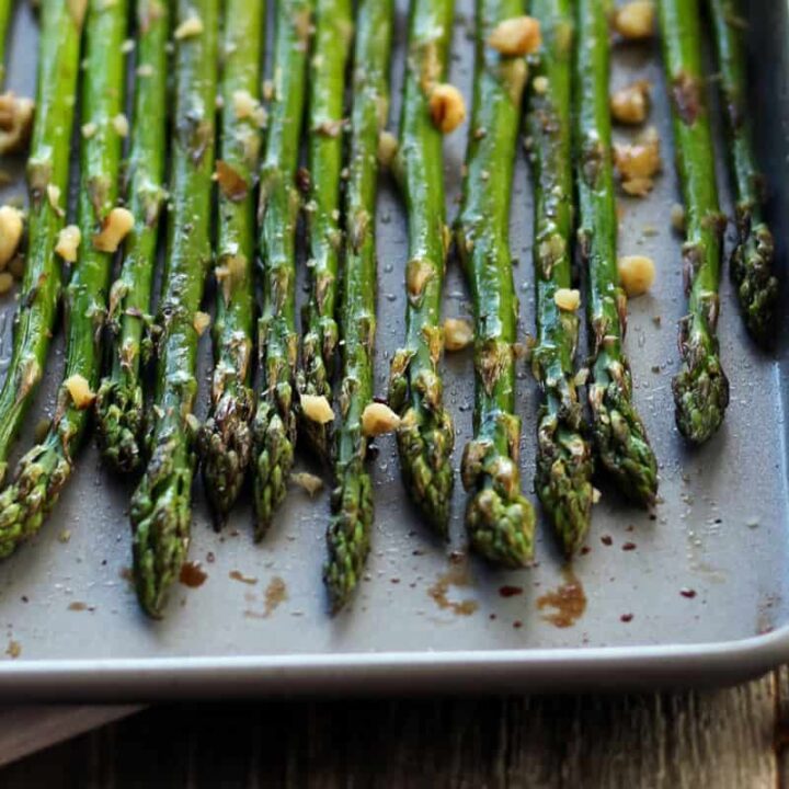Thin spears of roasted asparagus on a small sheet pan.